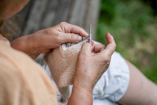 Elderly woman knitting in the garden