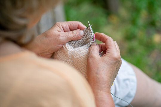 Elderly woman knitting in the garden