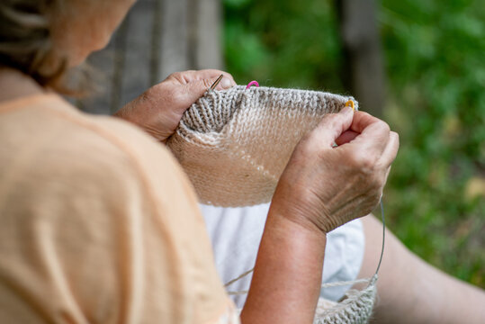 Elderly woman knitting in the garden