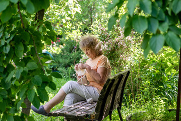 Elderly woman knitting in the garden