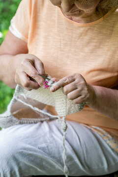 Elderly woman knitting in the garden