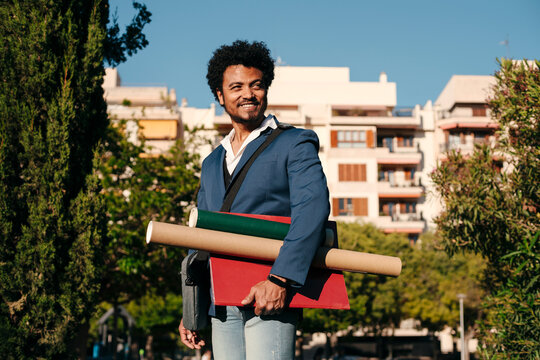Professional man holding folders and portfolio tubes