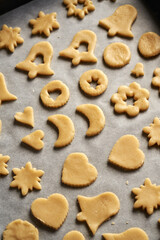 Shapes made of raw pastry dough on a sheet of baking paper - preparation of Linzer Christmas cookies