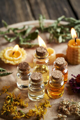 Essential oil bottles with beeswax candles and dry herbs