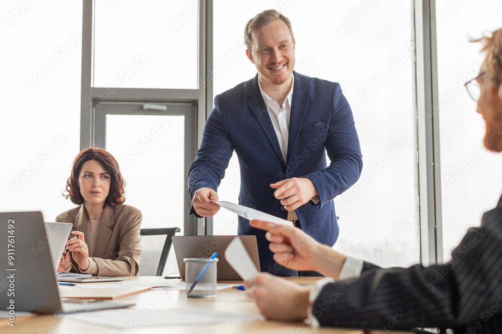 Aufkleber a man wearing a blue suit stands in front of a table in a modern office. he smiles as he presents a 