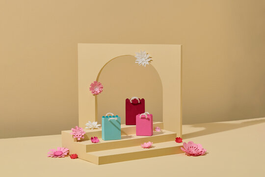 Three pink shopping bags with paper flowers on display.