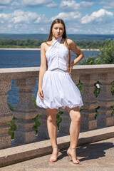Portrait of a young beautiful blonde woman in a white dress