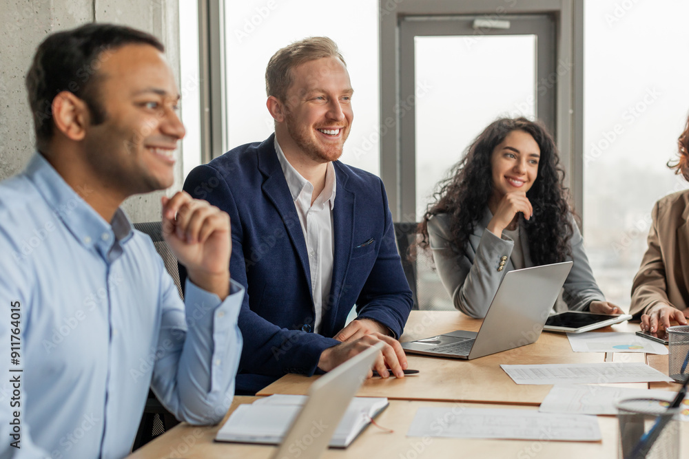 Aufkleber four smiling colleagues are sitting around a table, engaged in a conversation during a meeting. the 