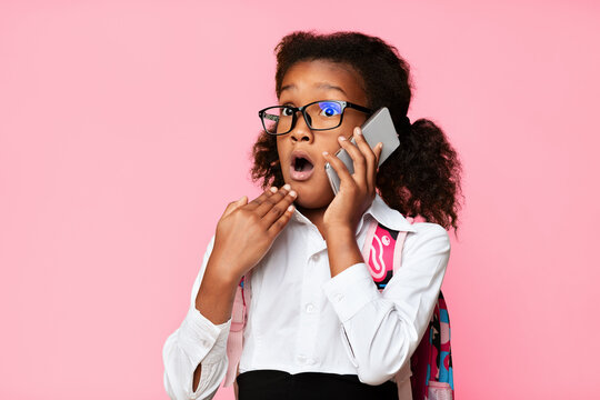 OMG, School News. Surprised Afro Schoolgirl Talking On Phone Over Yellow Studio Background. Free Space