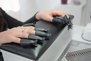 Process removing gel polish from nails in a beauty salon close up. Woman hands with set of plastic...