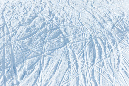 Snowy abstract off-piste skiing background with ski and snowboard trails and tracks on new virgin powder snow. morning sunrise or evening sunset time at alpine mountain resort - Powered by Adobe