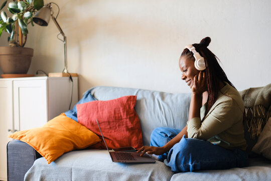 Woman at home living room with headphones and computer