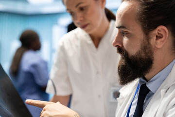 Radiology experts looking at x ray scan results to put the right diagnosis, planning treatment options. Team of licensed medics examining healthcare records and working on recovery.