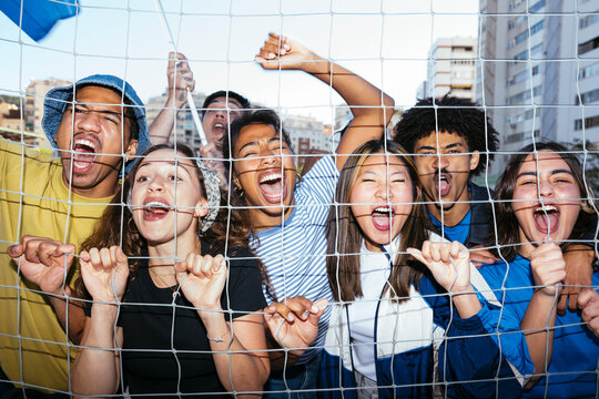 Group of people cheering behind fence at sporting event