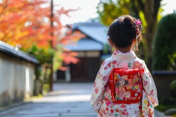 Fototapeta premium 紅葉が色づく公園で、着物を着た少女が楽しそうに歩いている。カラフルなバッグが彼女の後ろに揺れている。