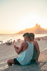 lgtb gay couple sitting on the beach ipanema rio de janeiro