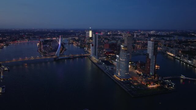 Rotterdam skyline and erasmus bridge at twilight, showcasing city lights reflecting on the river. Urban architecture and modern city living