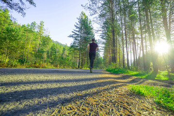 Running man jogging in city park at beautiful summer day. Sport fitness model caucasian ethnicity training outdoor.