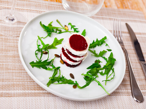 Appetizing appetizer of French cuisine is Milfey of beetroot with goat cheese, decorated with arugula