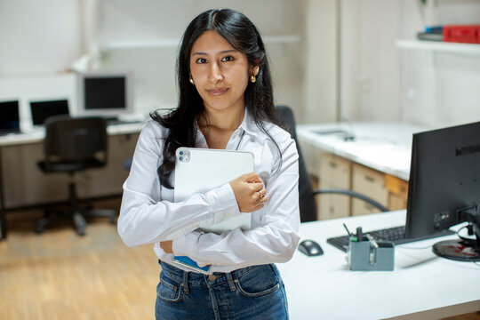 Corporate portrait of smiling woman in office looking at camera