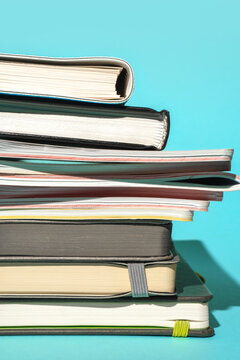 Stack of various notebooks on blue background with copy space.
