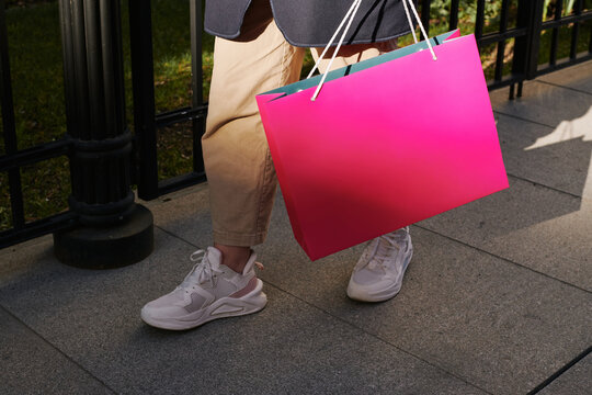 Person Carrying Pink Shopping Bag on Sidewalk