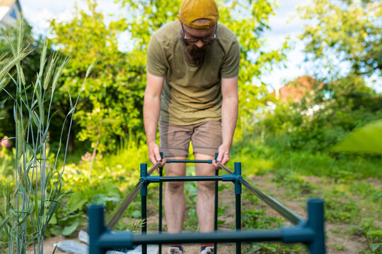 man in the garden assembling a greenhouse