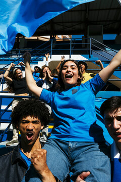 Excited female fan being carried by friends in stadium