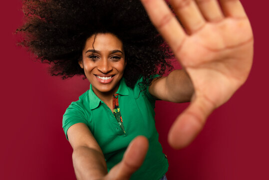Woman smiling with hands outstretched against a red background