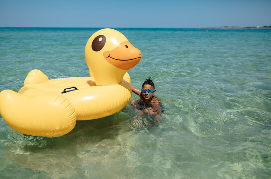 
boy in the sea with a large inflatable duck