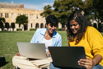 College Friends Sitting On The Grass And Working On Laptop
