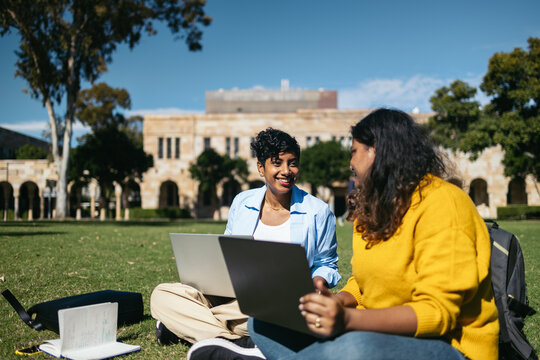 University Students sitting on the grass using laptop