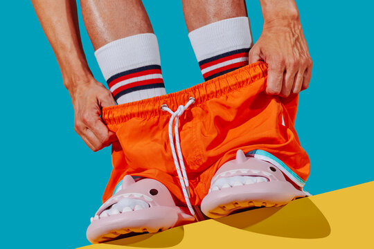 pulls down his trunks, wearing socks and sandals