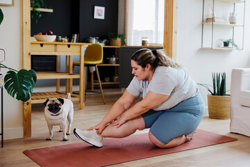 Curvy woman stretching exercises on yoga mat at home