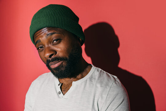 Man wearing a green beanie posing against a red background