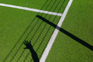 Hand drops deep shadow onto green sport field