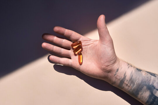 Male hand holding pills in sunlight. Studio shot with copy space