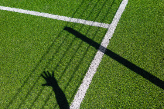 Hand drops deep shadow onto green sport field