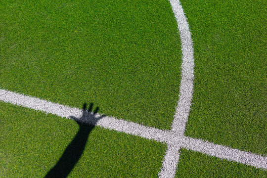 Hand drops deep shadow onto green sport field