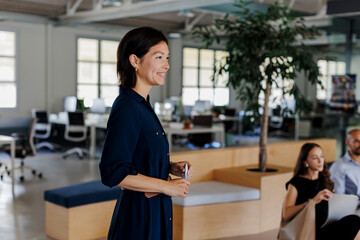 Smiling businesswoman leading brainstorming during meeting at office