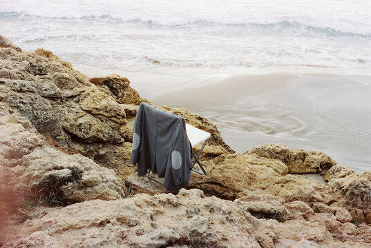 jacket on a folding chair, on a rocky coast, 35mm