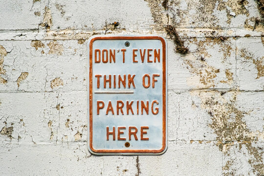 "Don't even think of parking here" sign on old cinderblock wall