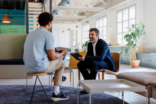 Businessmen smiling and talking about work in the office