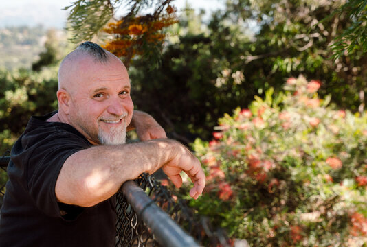Smiling Man Leaning on Fence in Garden