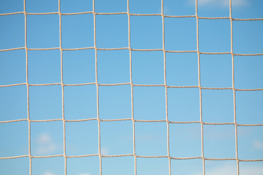 Close-Up Texture of Football Goal Net Against Blue Sky
