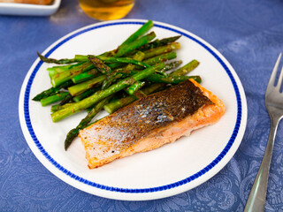 Tasty grilled salmon steak with asparagus garnish served on white plate