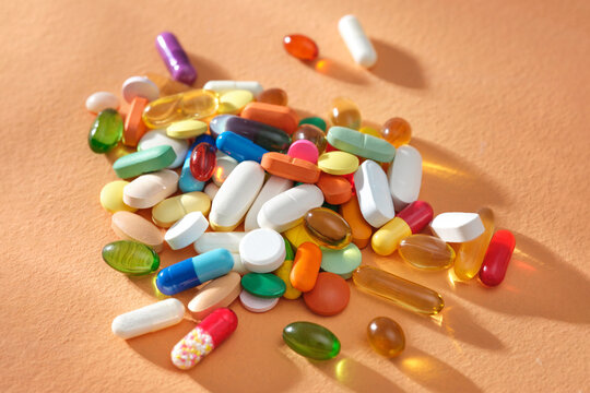 A lot of pills of different colors and shapes stacked together