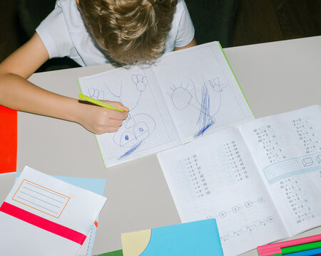 A boy draws in his copybook instead of solving math examples.