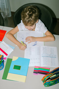 A boy draws in his copybook instead of solving math examples.