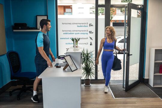 woman entering at a gym where her personal trainer receives her